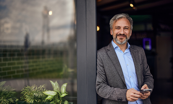 A professionally dressed man in his late-40s looks ahead while smiling, happy that he's working on his financial wellness.