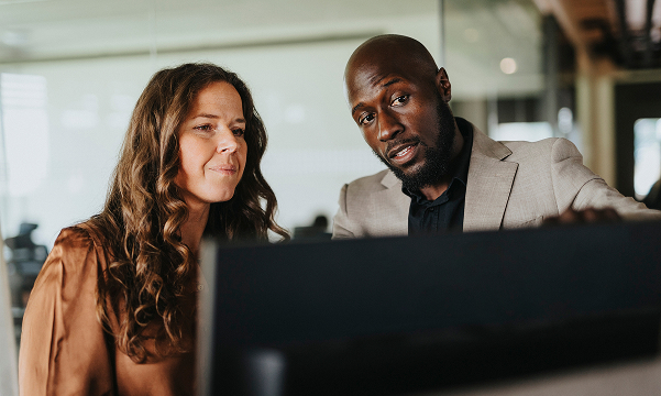 A male plan representative and a female plan participant look at a monitor, walking through a unique plan situation.
